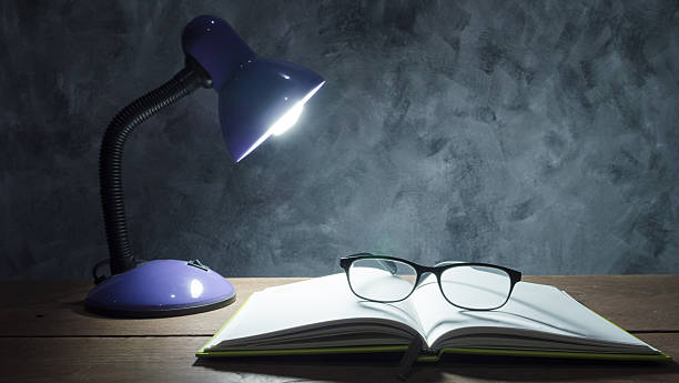istock Lamp with notebook and glasses on wooden table 615610774