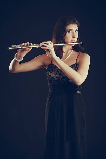 istock Woman playing transverse flute on black. 615611730