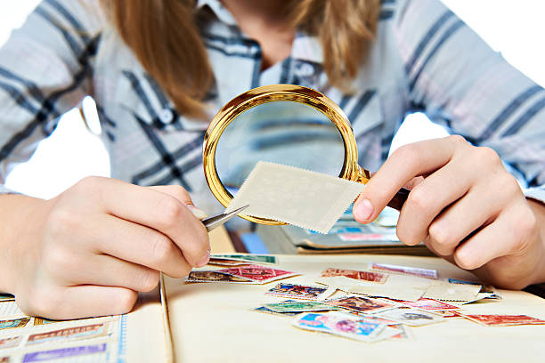 Teen girl with magnifier looks his stamp collection Teen girl with magnifier looks his stamp collection  isolated stamp collecting stock pictures, royalty-free photos & images