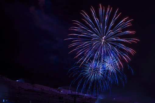 Brightly colorful fireworks. Night skiing.  Panoramic view of  high mountain winter landscape .