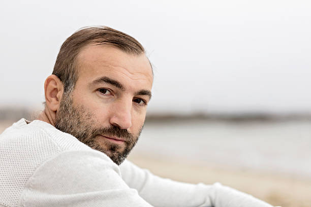 istock Male (brunette) with a beard in a white sweater looking 615615274