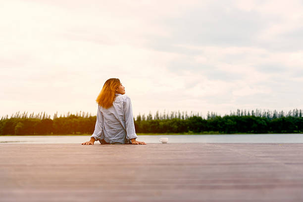 istock Girl drinks tea on wood balcony by river 615622278