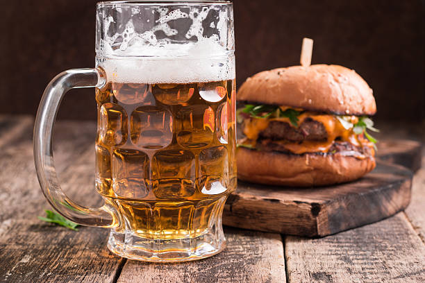Fresh hamburger with a beer on a wooden table.