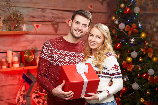 istock young couple in sweaters embracing and holding red giftbox 615632816