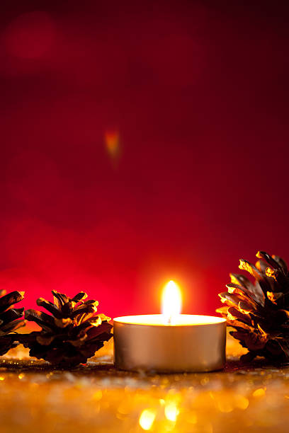 istock Candle and pinecones on dark red background 615637192