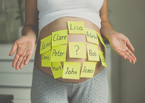 Tiro tonizado de la mujer embarazada con nombres del niño en vientre photo