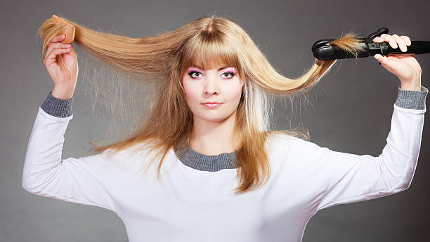 istock woman making hairstyle with hair iron 615638908
