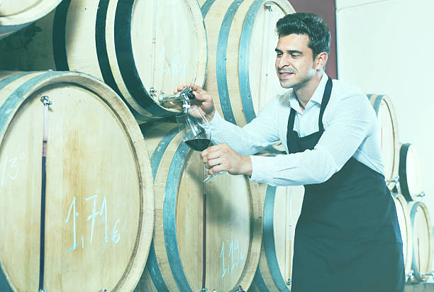 istock Man pouring red wine into glass in alcohol section 615639098