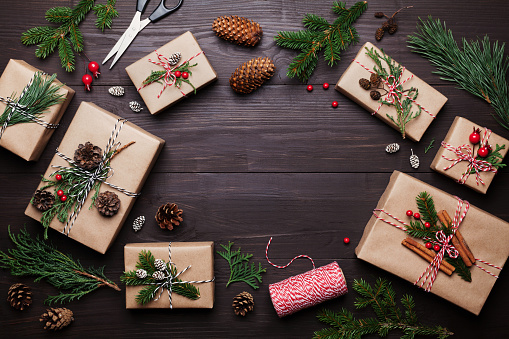 Gift or present box wrapped in kraft paper with christmas decoration on rustic wooden background from above. Flat lay style.
