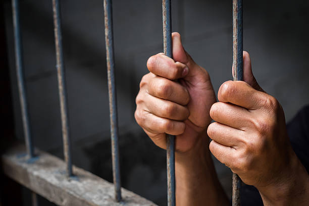 istock Hands of man behind jail bars. 615639420