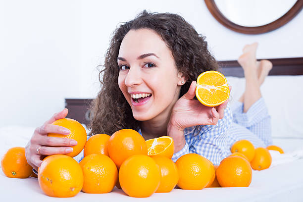istock Positive girl eating oranges in bed 615640490