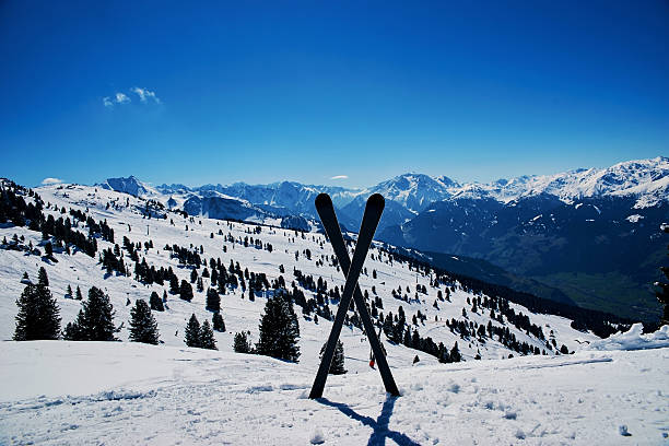 Crossed skis standing in snow in mountains. View on snowy slopes at skiing resort. Vacation concept