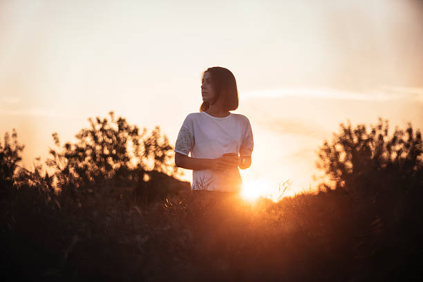 istock Young brunette standing in the sunset summer field, contemplating 615703470