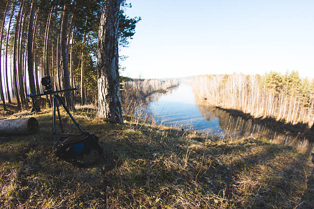 istock Camera standing on tripod at morning forest river landscape, spring 615705172