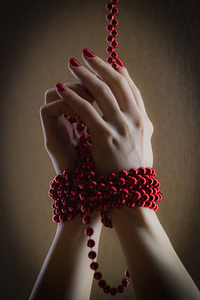 istock Girl has hands bound with red beads - close up 615705768
