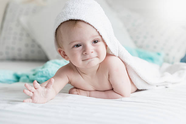 istock Happy 9 months baby lying under white towel on bed 615706722