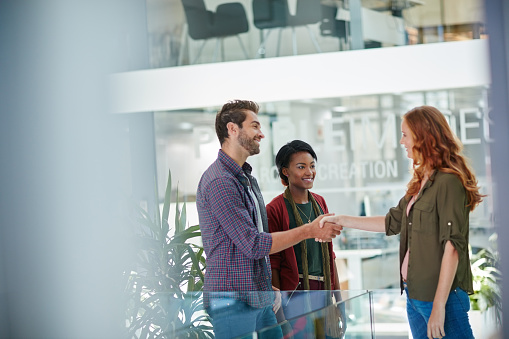 Shot of a team of creative businesspeople meeting a new teammember in the office