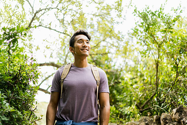 escursionista sorridente fiducioso in piedi contro gli alberi - hiking adventure outdoor pursuit backpacker foto e immagini stock
