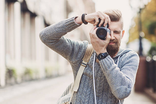 Young man photographer looking at camera Young man photographer holding a camera and taking pictures slr camera photos stock pictures, royalty-free photos & images