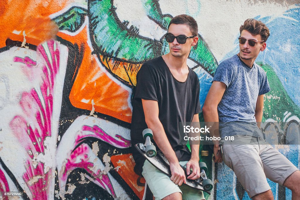 Rebel teenagers standing against brick wall Rebel teenagers standing against brick wall and holding skateboards in their hands. Skateboarding Stock Photo