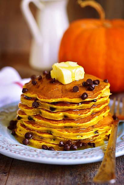 Pumpkin pancakes with chocolate drops on a rustic background.