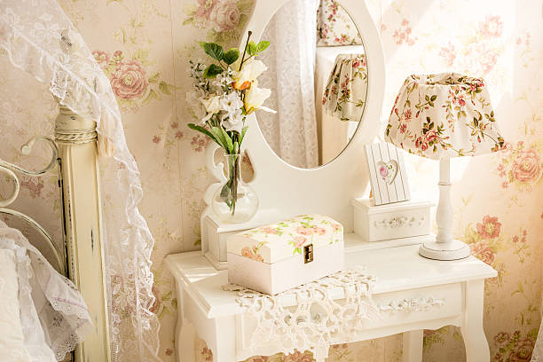 Elegant interior scene featuring a white dresser styled with blue and white ceramic vases, decorative photo frames, and stacked books, set against a soft blue wall. An ornate, gold-framed wall mirror adds a classic touch while reflecting subtle patterned textures.