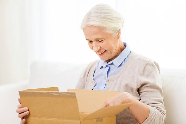 istock happy senior woman with parcel box at home 615726830