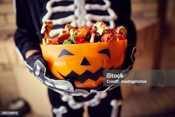 Niño Disfrazado De Esqueleto Sosteniendo Cuenco Lleno De Caramelos Foto de stock y más banco de imágenes de Halloween