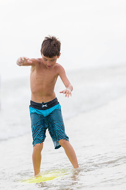 istock Boy balances on body board in the ocean 615729508