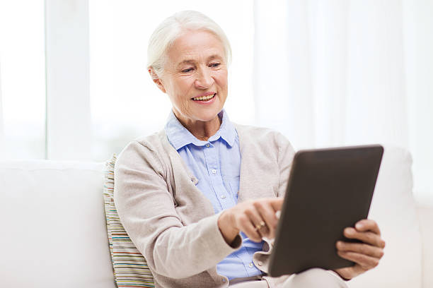 istock happy senior woman with tablet pc at home 615730808