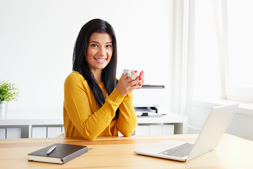 Smiling woman drinking coffee in the office