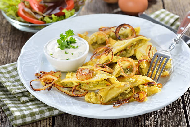 Fried Swabian ravioli (so-called'Maultaschen') with vegetarian filling served with roasted onions, scrambled egg and creamy herb cheese