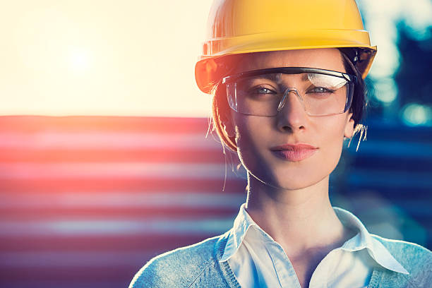 Woman civil engineer or architect beautiful woman civil engineer or architect with yellow protective industrial helmet and protective glasses close up civilian stock pictures, royalty-free photos & images