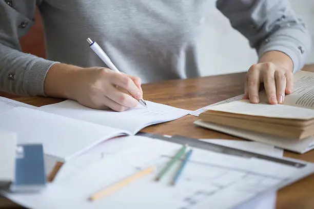 Photo of Student female hands performing a written task in a copybook