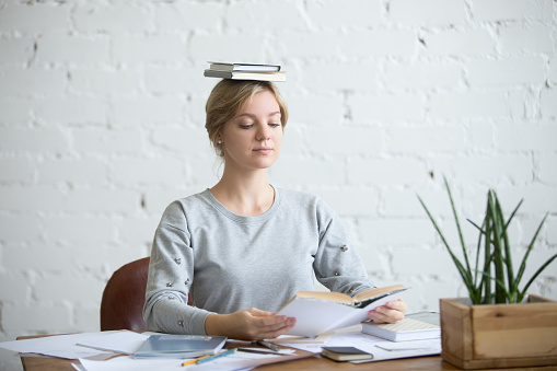 Retrato de una mujer atractiva en el escritorio, libros en la cabeza photo