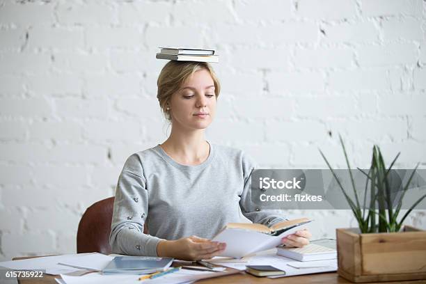 Portrait Of Attractive Woman At Desk Books On Her Head Stock Photo - Download Image Now