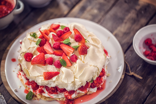 Berry Pavlova Cake with fresh strawberries, raspberries, mint leaves and whipped cream.