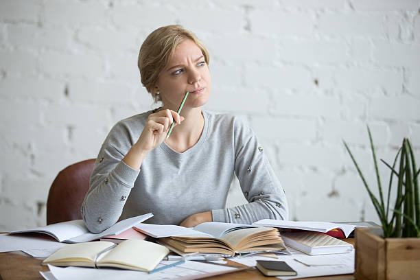 Portrait of a student woman at the desk, frowned Portrait of a student woman sitting at the desk, frowned, looking aside lifestyle. Education concept photo forget thing stock pictures, royalty-free photos & images