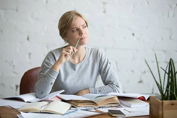 Portrait of a student woman sitting at the desk, frowned, looking aside lifestyle. Education concept photo