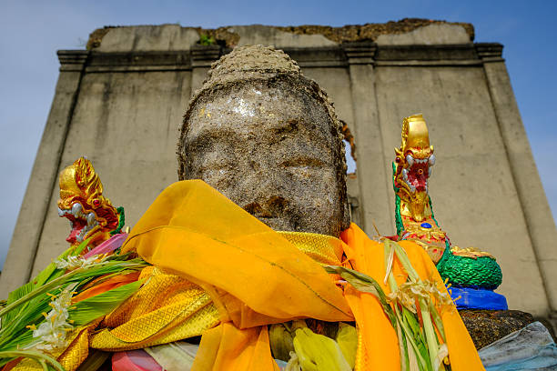 istock Public ancient head Buddha statue left in the forest 615737594