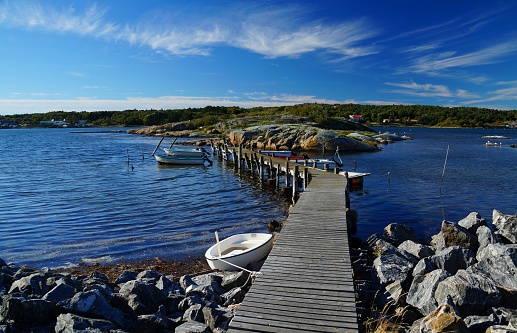 Wooden pier with small, moored ships between bare rocks on the seaside of Donsö, an island of the archipelago of Gothenburg (Göteborgs skärgård), Sweden