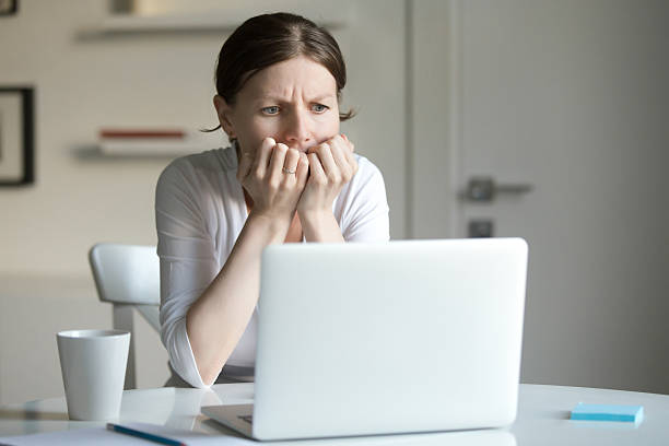 porträt einer jungen frau am schreibtisch mit laptop, angst - fear terrified shock humor stock-fotos und bilder