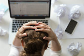 Portrait of woman grabbing head at desk near the laptop