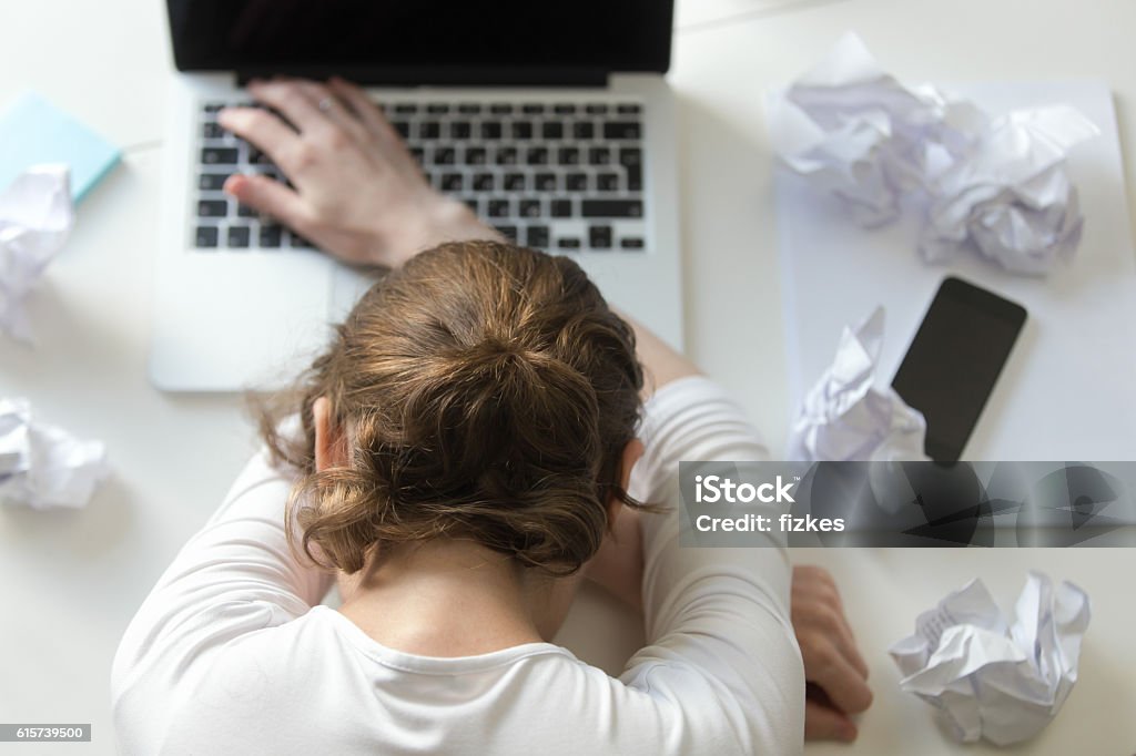 Top view portrait woman lying at desk near the laptop Top view portrait of a woman lying at the desk near the laptop. Education, business concept photo. Lifestyle Falling Stock Photo