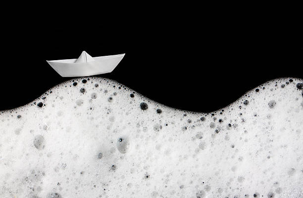istock Foam bubbles abstract black background. Detergent. White textile boat. Wash. 615739976