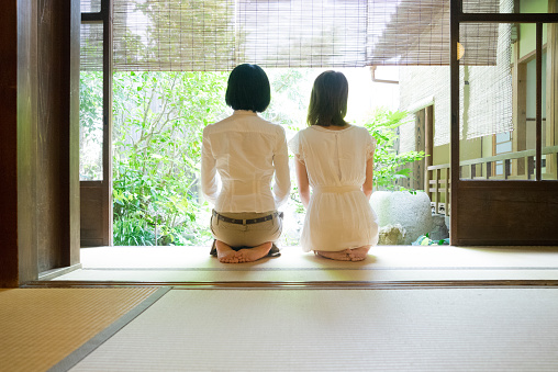 Two Japanese women contemplating the garden from the veranda in a traditional house.