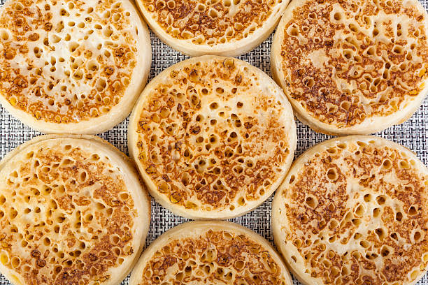 Close up of fresh golden crumpets on a black and white woven table mat