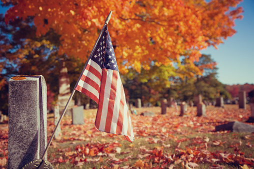 American veteran flag in autumn cemetery. Vintage filter effects.