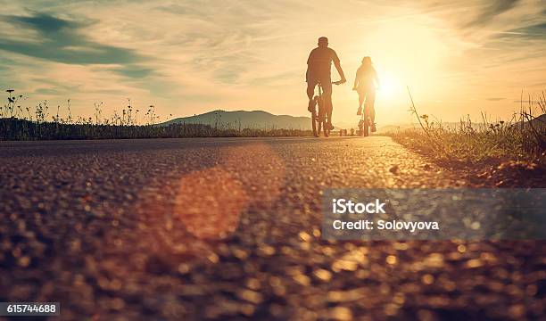 Cyclists Are On The Sunset Road Stock Photo - Download Image Now - Bicycle, Cycling, Family