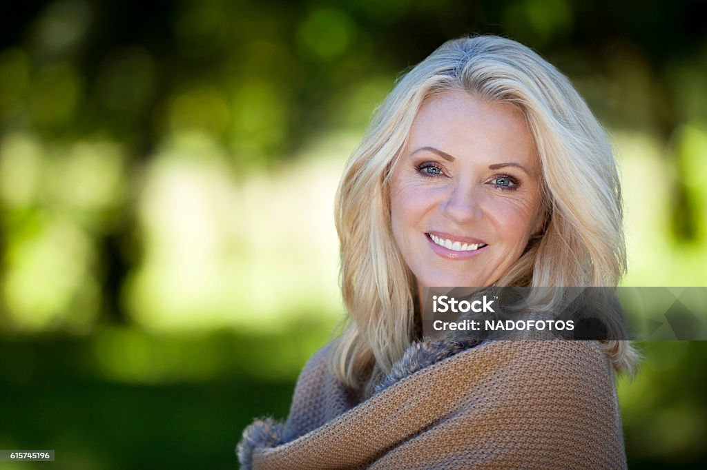 Retrato de uma mulher madura sorrindo para a câmera no parque - Foto de stock de Modelo profissional royalty-free